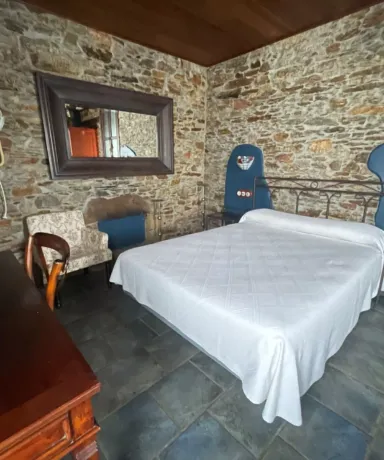 Habitación con escritorio, cama grande, sillón, espejo, secador de pelo y mesillas de noche